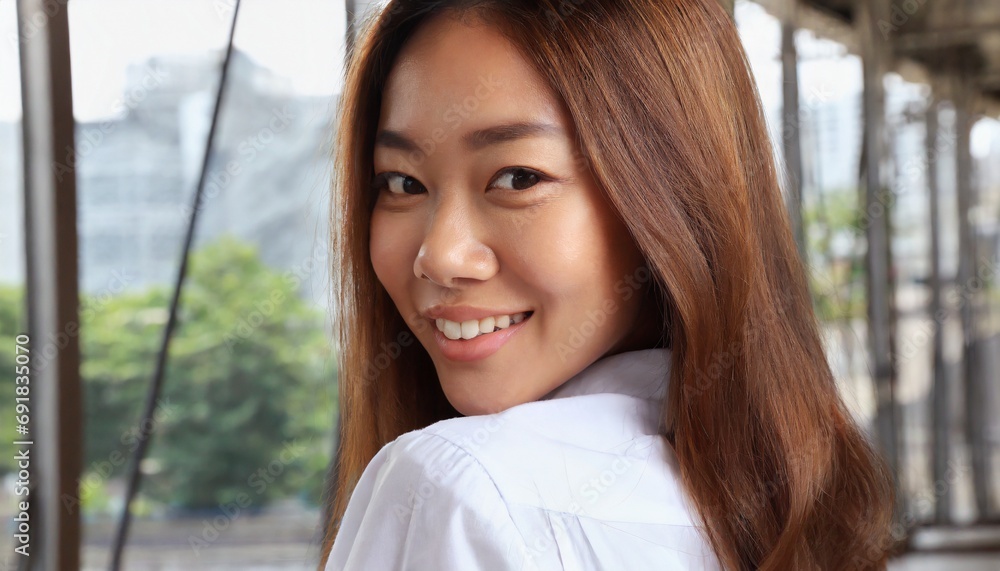  Young Asian woman with brown hair in white shirt, smiling