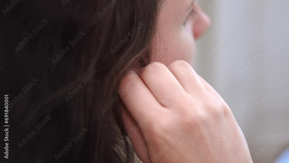 Attractive brunette puts in earphone with wire for music, close up view Attractive brunette puts in earphone with wire for music, close up view