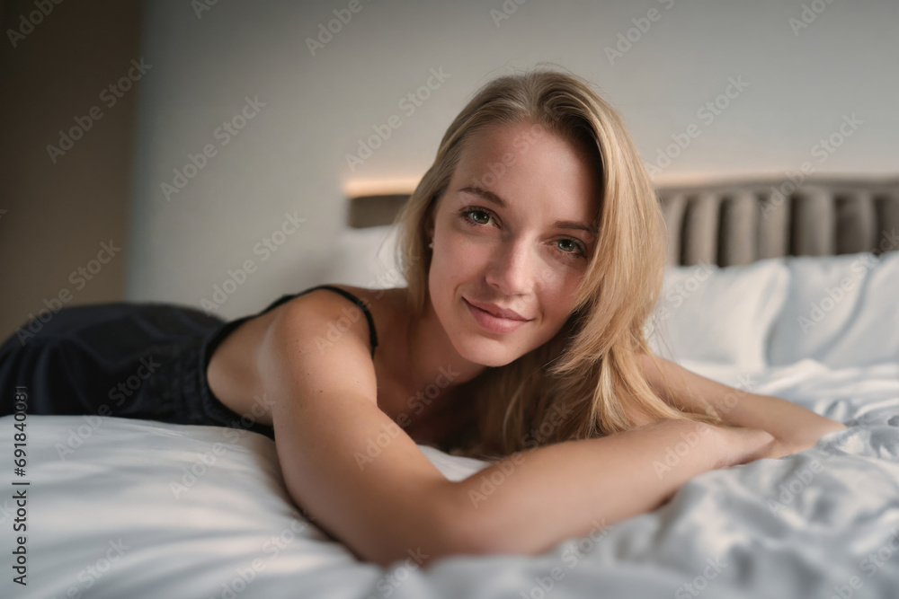 Young, inviting woman on hotel bed, relaxed and content Young, inviting woman on hotel bed, relaxed and content