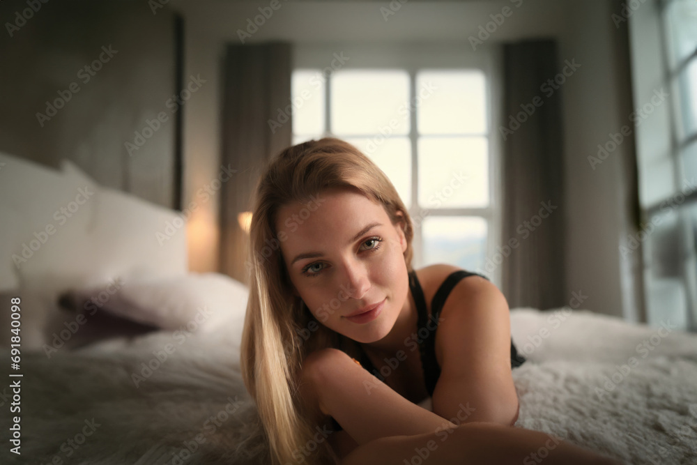 Young, inviting woman on hotel bed, relaxed and content Young, inviting woman on hotel bed, relaxed and content