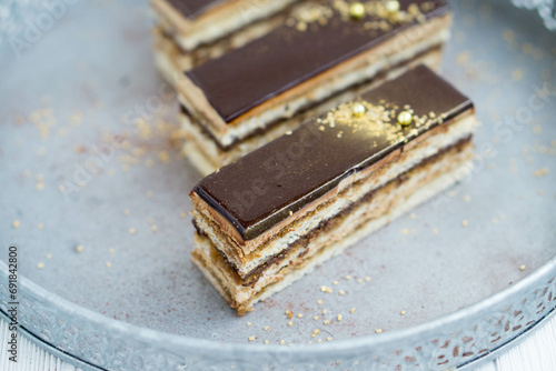 Classic french pastry opera layered cake with almond sponge soaked in coffee syrup, buttercream  ama chocolate ganache layers, and topped with a glossy chocolate glaze close up selective focus