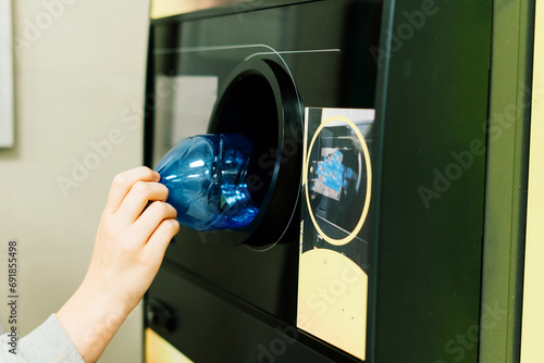 Reverse vending recycling machine that dispenses cash. Man hand puts plastic bottle to the machine