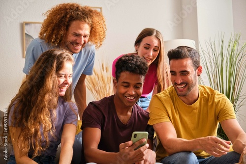 Group of cheerful young multiethnic friends watching social network funny content on a smartphone screen.