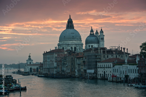 Light orange and pink sunset reflected in the water in Venice, with clear cityscape and architecture in detail