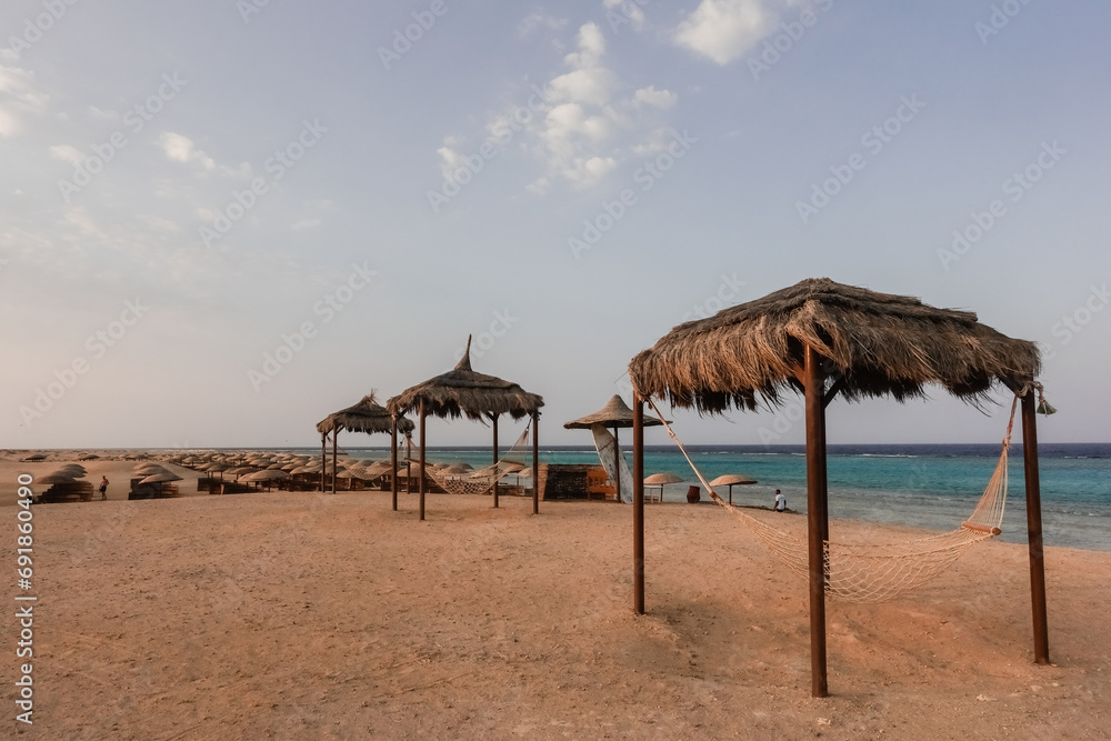 three cozy hammocks with a reed roof at the sandy beach at the red sea