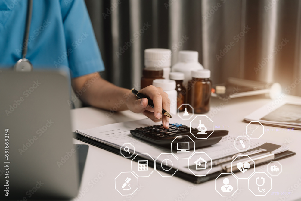 Healthcare costs and fees concept.Hand of smart doctor used a calculator for medical costs in modern hospital with VR icon diagram. Healthcare costs and fees concept.Hand of smart doctor used a calculator for medical costs in modern hospital with VR icon diagram.