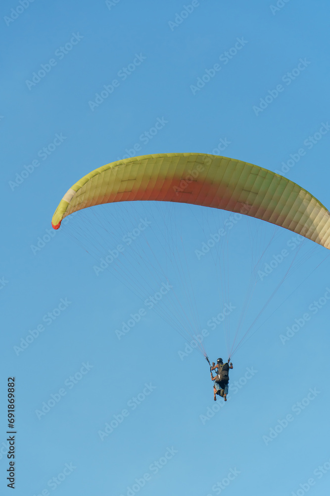 Paragliding in the sky over the sea. The concept of parachute flight. Tandem skydiver pilot and passenger fly on a sunny day. Paragliding in the sky over the sea. The concept of parachute flight. Tandem skydiver pilot and passenger fly on a sunny day.
