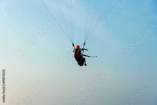 Paragliding in the sky over the sea. The concept of parachute flight. Tandem skydiver pilot and passenger fly on a sunny day.