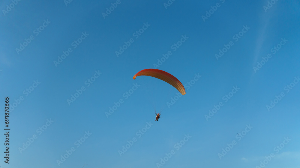 Paragliding in the sky over the sea. The concept of parachute flight. Tandem skydiver pilot and passenger fly on a sunny day. Paragliding in the sky over the sea. The concept of parachute flight. Tandem skydiver pilot and passenger fly on a sunny day.