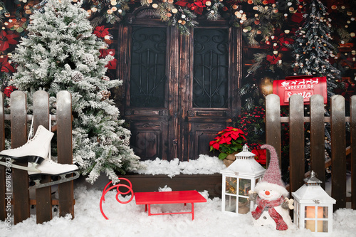 An old wooden pivot door is decorated brightly with christmas and new years decoration the place seen from the exterior typical christmas wreath and ornamental decoration, snowman and christmas tree photo