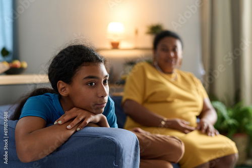 Adult daughter having a conflict with her mother while sitting on sofa in the room