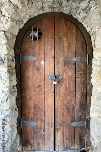 ancient wood cellar door in an arched stone wall photo