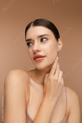 Portrait of smiling woman with natural makeup, stylish hairstyle posing in studio. Isolated on beige background. Skin care, beauty procedure, morning routine