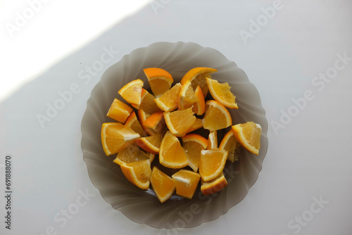 Sliced ​​orange on a platter on a white background, shadow