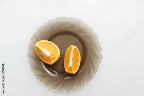 Two slices of orange on a platter on a white background