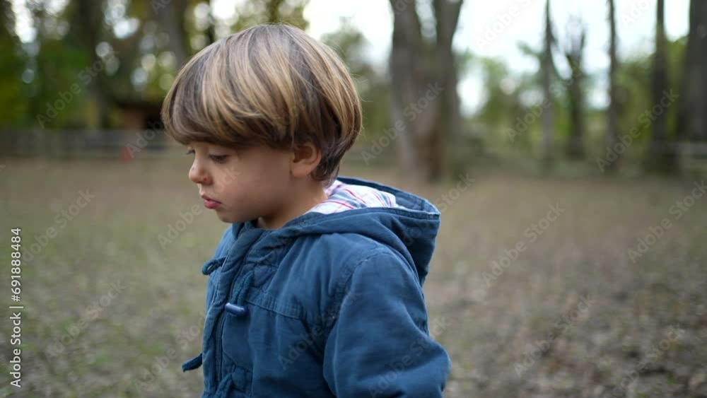 Sad pensive child walks forward outside at park during fall season. Thoughtful kid in great outdoors feeling worry Sad pensive child walks forward outside at park during fall season. Thoughtful kid in great outdoors feeling worry