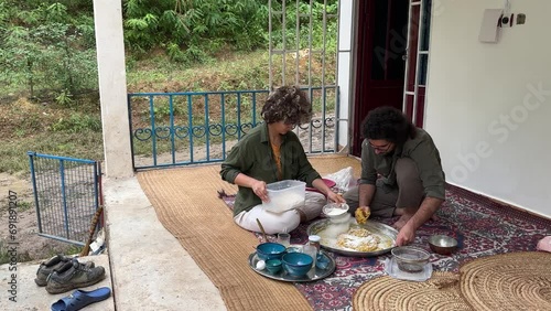 A couple prepare to make sour dough wheat flour and fermentation to bake flat Turkish bread Iran country life country side rural town village people local skill bakery outside in clay wood fire oven photo