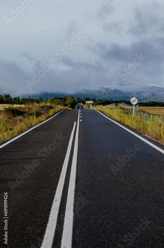 straight road towards cloud-covered mountains photo