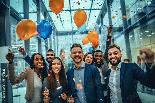 Group of young confident successful business people with balloons celebrating achievement. Business event or party at office hall. photo