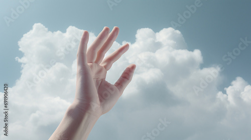 An image of a hand reaching towards the sky, holding a cluster of soft, fluffy white clouds in its grasp.