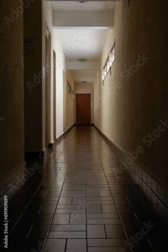 Corridor with closed doors of an empty building without people. A long narrow hallway of a hotel.