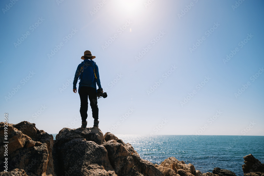 Obraz premium Woman photographer enjoy the view on sunrise seaside rocks