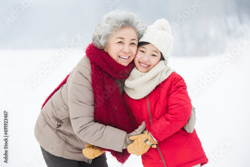 Happy grandmother and granddaughter embracing on the snow