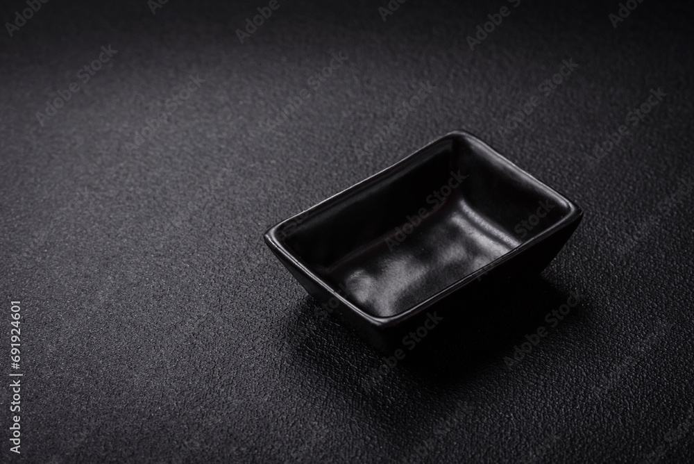 Beautiful empty black ceramic gravy boat on a textured concrete background Beautiful empty black ceramic gravy boat on a textured concrete background