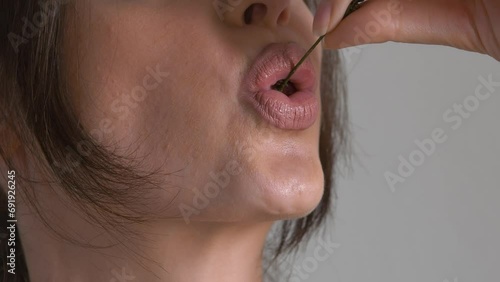 Close-up of woman's mouth biting off red ripe cherry photo