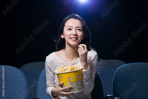 Young woman watching movie in cinema with popcorn in hand photo