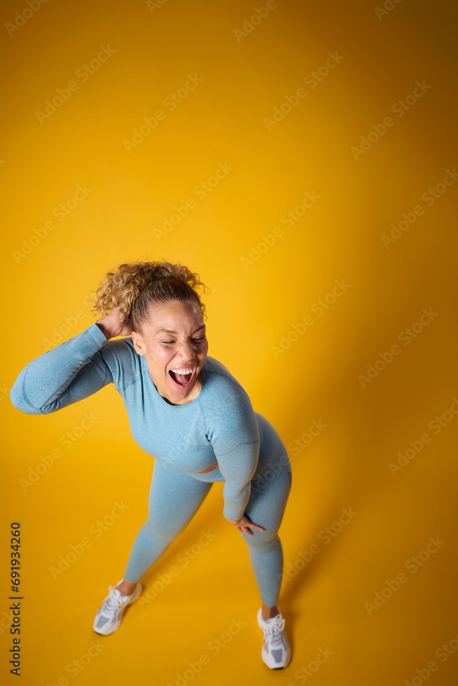 Studio Full Length Portrait Of Woman Wearing Gym Fitness Clothing Exercising On Yellow Background Studio Full Length Portrait Of Woman Wearing Gym Fitness Clothing Exercising On Yellow Background