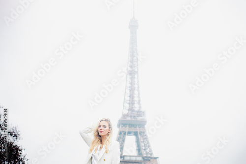 Pretty blonde girl with long hair poses against background of sky and Eiffel Tower.Tourism.  © Татьяна Волкова