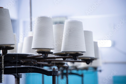White Cotton Spools of Thread on the industrial knitting factory machine stand
