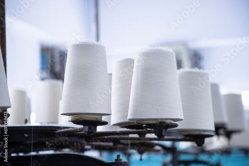 White Cotton Spools of Thread on the industrial knitting factory machine stand