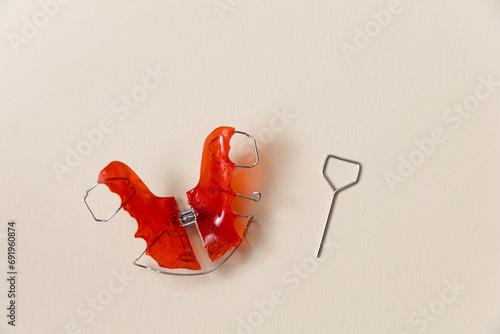 Red retainer or jaw expander on the background. Crooked teeth correction concept and bite correction in humans.