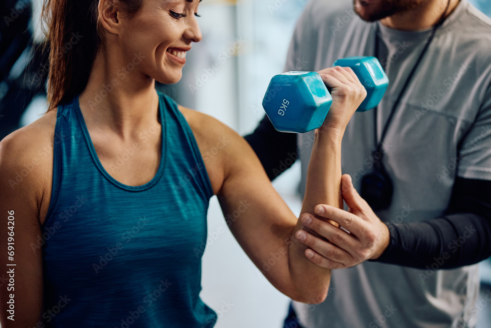 Close up of fitness instructor assisting sportswoman is exercising with hand weights in gym. Close up of fitness instructor assisting sportswoman is exercising with hand weights in gym.