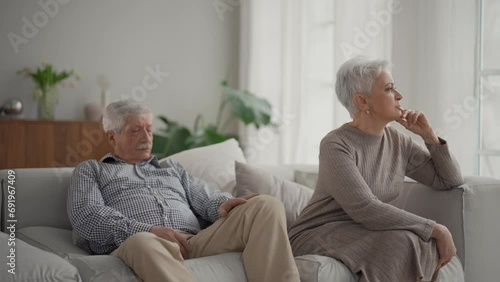 Senior sad couple separate on couch ignoring each other, avoid talking after fight and quarrel. Wife and husband have misunderstandings, experiencing relationship crisis. Upset elderly family at home. photo