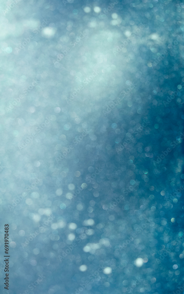 Defocused abstract blue and white bokeh sparkling christmas lights, vertical