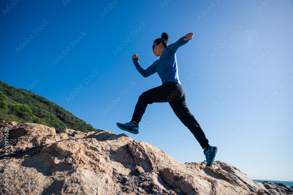 Woman runner running on sunrise seaside rocky mountains Woman runner running on sunrise seaside rocky mountains