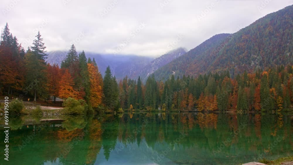 Tranquil autumn lake with reflection of colorful foliage and mountains under overcast sky. Tranquil autumn lake with reflection of colorful foliage and mountains under overcast sky.