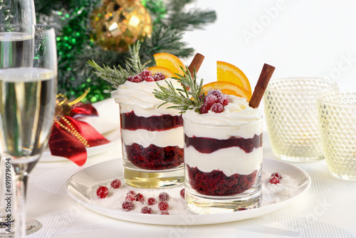 Christmas cranberry dessert tiramisu with mascarpone and whipped cream, chocolate biscuit crumble and cranberry jam, garnished with orange slices, candied cranberries and rosemary.