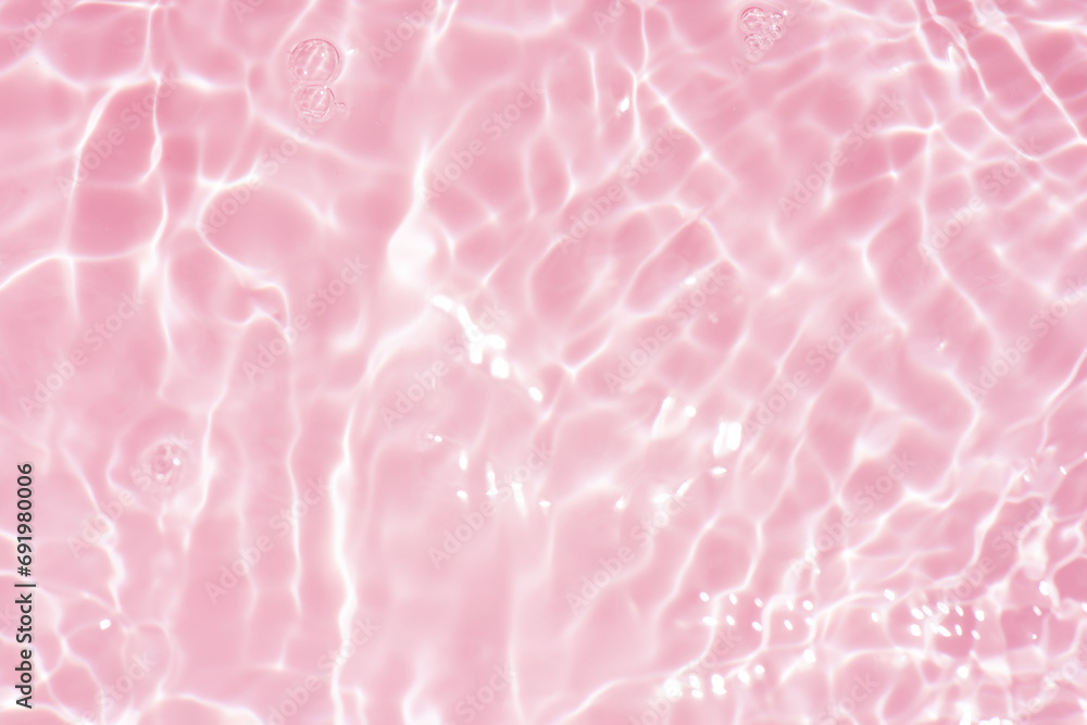 Pink water bubbles on the surface ripples. Defocus blurred transparent pink colored clear calm water surface texture with splash and bubbles. Water waves with shining pattern texture background