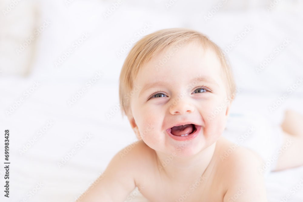 laughing or smiling baby boy blond with big eyes close-up or portrait in a crib at home, the concept of children's goods and accessories laughing or smiling baby boy blond with big eyes close-up or portrait in a crib at home, the concept of children's goods and accessories