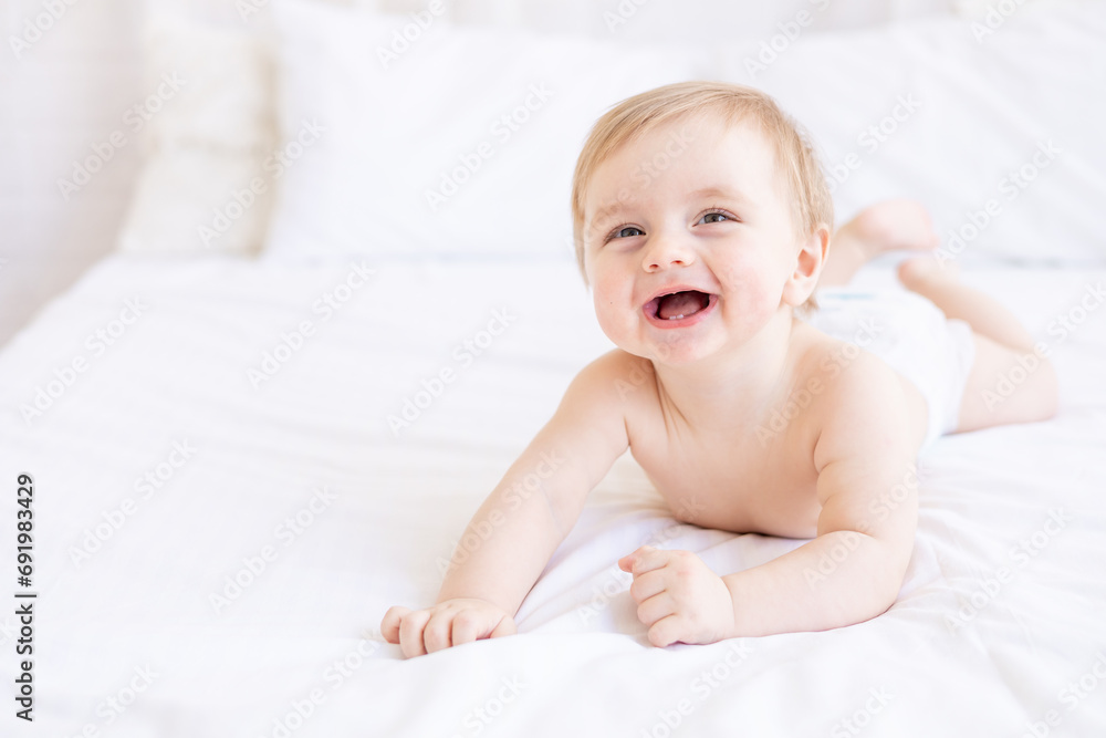 laughing or smiling baby boy blond with big eyes close-up or portrait in a crib at home, the concept of children's goods and accessories laughing or smiling baby boy blond with big eyes close-up or portrait in a crib at home, the concept of children's goods and accessories