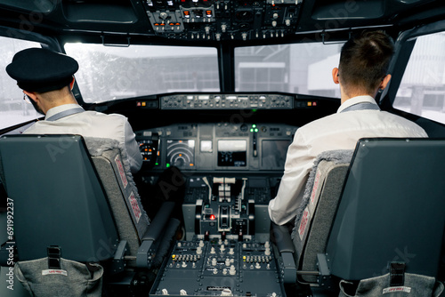 Airplane cabin Pilots check airplane electronics by pressing buttons Passenger airliner preparation for takeoff rear view flight simulator photo