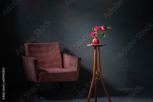 pink roses in pink vase with old armchair on background dark wall