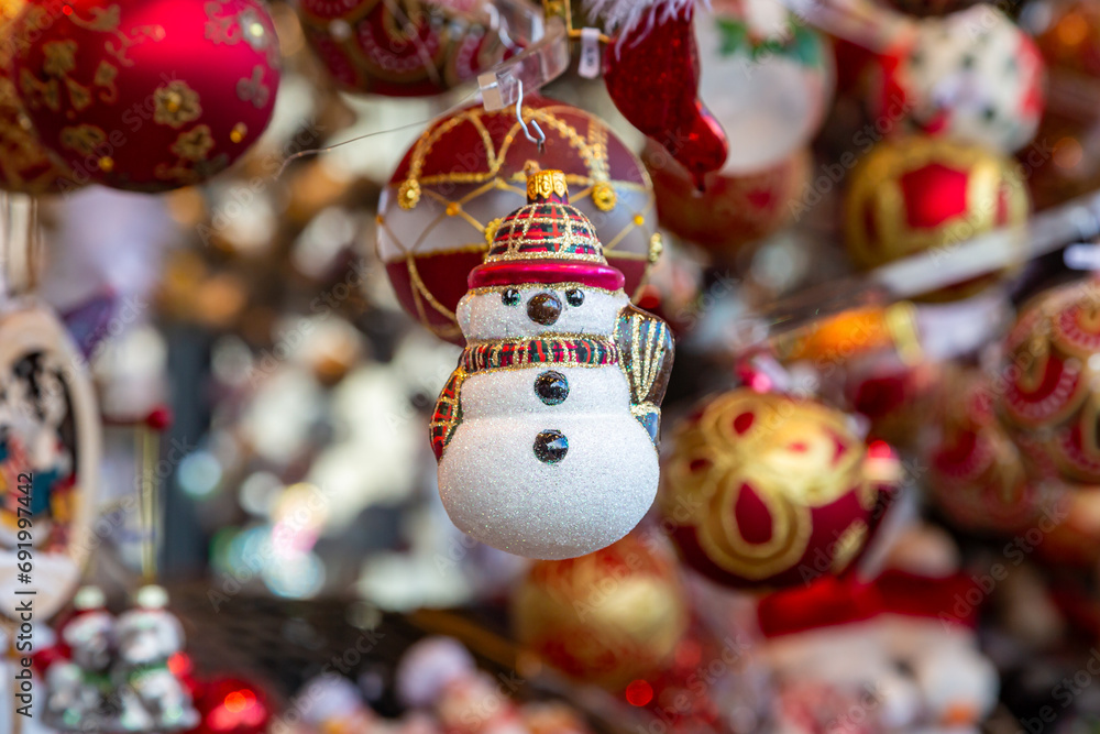 A snowman shaped Christmas bauble on a market stall, with a shallow depth of field