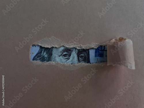 Paper torn and revealing dollar bill