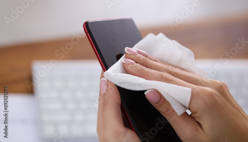 Cuadro en lienzo Woman wiping screen of mobile phone with damp cloth closeup