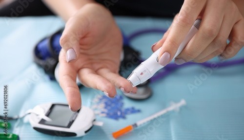 Woman drawing blood with lancet at home closeup. Blood glucose control in diabetes mellitus concept photo